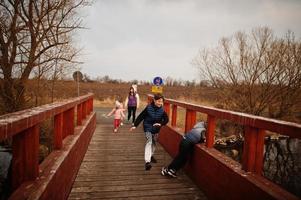 madre con niños caminando y divirtiéndose en el puente de madera junto al lago. foto