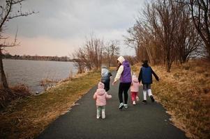 espalda de madre caminando con niños en el camino junto al lago. foto