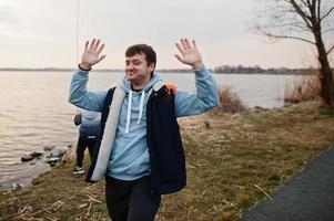 Funny man in blue hoodie with lollipop, shows different hand movements. photo