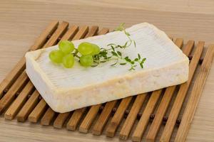 Brie cheese on wooden board and wooden background photo