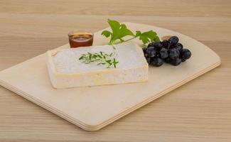 Brie cheese on wooden board and wooden background photo