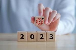 2023 new year challenge goal and target, Achievement and business success. Hand holding dartboard icon with 2023 word on wooden blocks. Happy new year 2023. Business and financial concept.