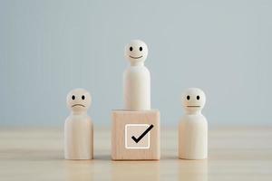 Select happy face figure on top of wooden blocks. Evaluation, Performance Appraisal, Skill, Success, Expert, Leadership. Human Resources management choosing positive attitude to team leader. photo