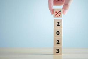 2023 new year challenge goal and target, Achievement and business success. Hand holding dartboard icon with stack of 2023 word on wooden blocks. Happy new year 2023. Business and financial concept. photo