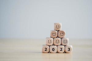 2023 bloques de madera con carita feliz. feliz año nuevo, feliz vida. emoción positiva de año nuevo. evaluación de la salud mental, día mundial de la salud mental, pensamiento positivo, experiencia, satisfacción y retroalimentación.
