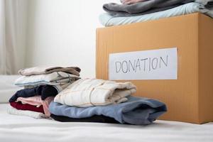 donación de ropa, compartir, concepto de esperanza. ropa usada en la caja de donación de cartón preparándose para otros foto