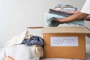 donación de ropa, compartir, concepto de esperanza. ropa usada en la caja de donación de cartón preparándose para otros foto