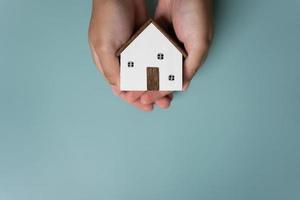 Hands holding small wooden house concept of protection or saving for new residential project. photo