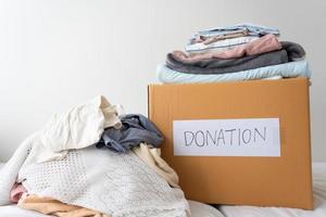 donación de ropa, compartir, concepto de esperanza. ropa usada en la caja de donación de cartón preparándose para otros foto