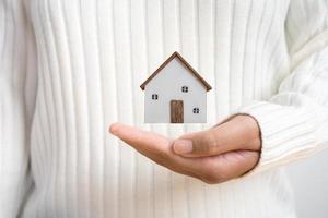 Hands holding small wooden house concept of protection or saving for new residential project. photo