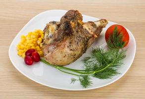 Roasted turkey leg on the plate and wooden background photo