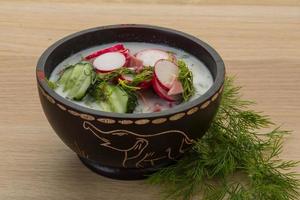 Okroshka in a bowl on wooden background photo