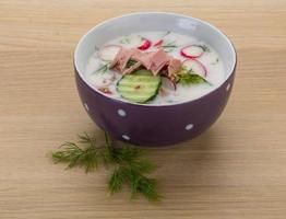 Okroshka in a bowl on wooden background photo