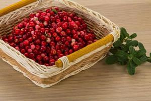 Cowberry in a basket on wooden background photo