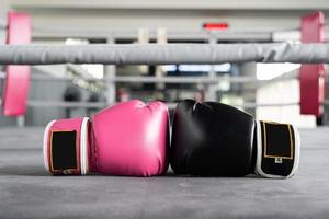 guante de boxeo rosa y negro en concepto de perforación en mujer. foto