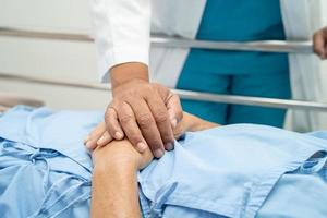 Tomados de la mano anciana asiática o anciana paciente con amor, cuidado, ánimo y empatía en la sala del hospital de enfermería, concepto médico fuerte y saludable foto