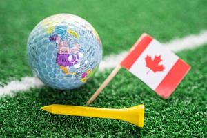 Golf ball with Canada flag and tee on green lawn or grass is most popular sport in the world. flag and tee on green lawn or grass is most popular sport in the world. photo