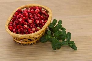 arándano rojo en una cesta sobre fondo de madera foto