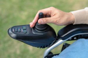 Asian lady woman patient on electric wheelchair with joystick and remote control at nursing hospital ward, healthy strong medical concept photo