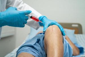 Asian doctor inject Hyaluronic acid platelet rich plasma into the knee of senior woman to walk without pain. photo