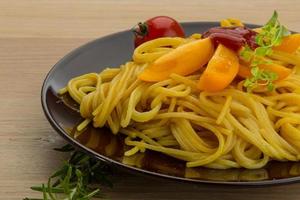 Vegetarian pasta on the plate and wooden background photo