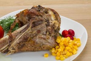 Roasted turkey leg on the plate and wooden background photo