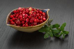 Cowberry in a bowl on wooden background photo