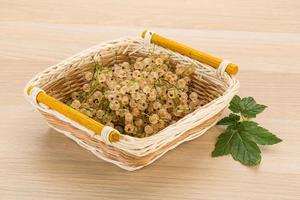 White currant in a basket on wooden background photo