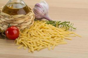 Raw pasta on wooden background photo