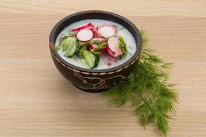 Okroshka in a bowl on wooden background photo