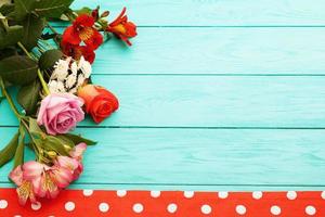 Frame of flowers and tablecloth in polka dots on blue wooden cooking workplace. Top view and selective focus. Copy space photo