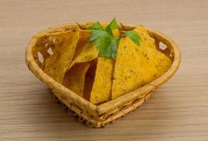 Nachos in a basket on wooden background photo