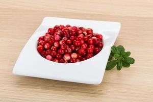 Cowberry in a bowl on wooden background photo