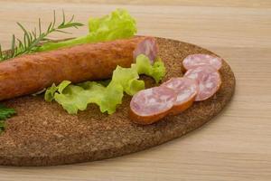 Sausage on wooden board and wooden background photo