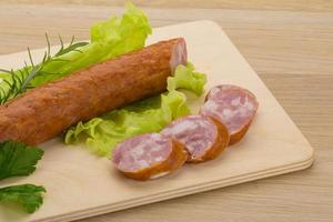 Sausage on wooden board and wooden background photo