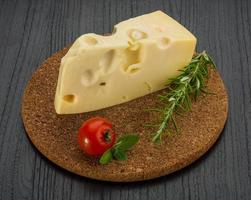 Maasdam cheese on wooden board and wooden background photo