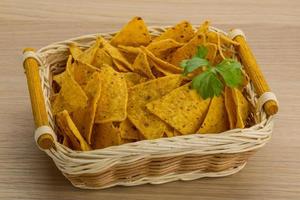 Nachos in a basket on wooden background photo