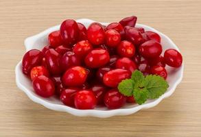 Cornus on the plate and wooden background photo