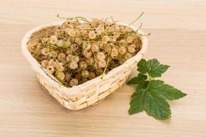 White currant in a basket on wooden background photo