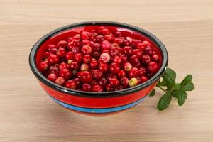 arándano rojo en un recipiente sobre fondo de madera foto