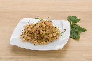 White currant on the plate and wooden background photo