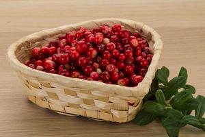 arándano rojo en una cesta sobre fondo de madera foto