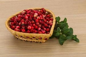 Cowberry in a basket on wooden background photo