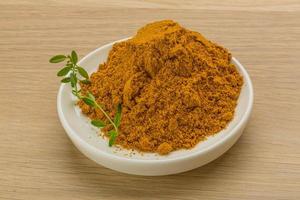 Curry powder on wooden background photo