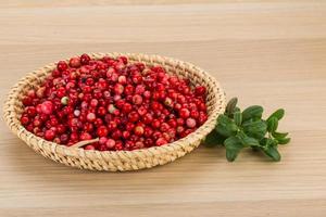 Cowberry in a basket on wooden background photo