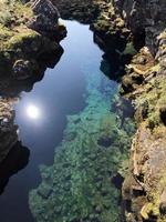 Agua clara y formaciones rocosas en Thingvellir, Islandia, en un día soleado foto