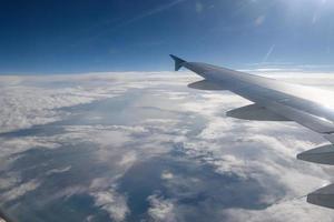 Wing of an airplane flying above the clouds photo