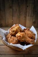 Fried Chicken in a basket on a wooden floor. photo