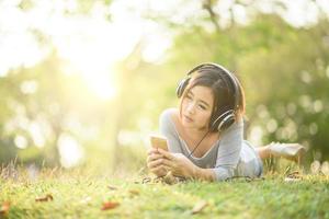 Young girl listening to music with headphone in city park photo