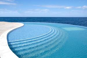 The wind makes water ripple. Sea water pool with stairs for relaxing. Blue clear water surface in swimming pool. Summer Vacation and rest concept. Pattern of bottom made of mosaic ceramic blue tiles. photo